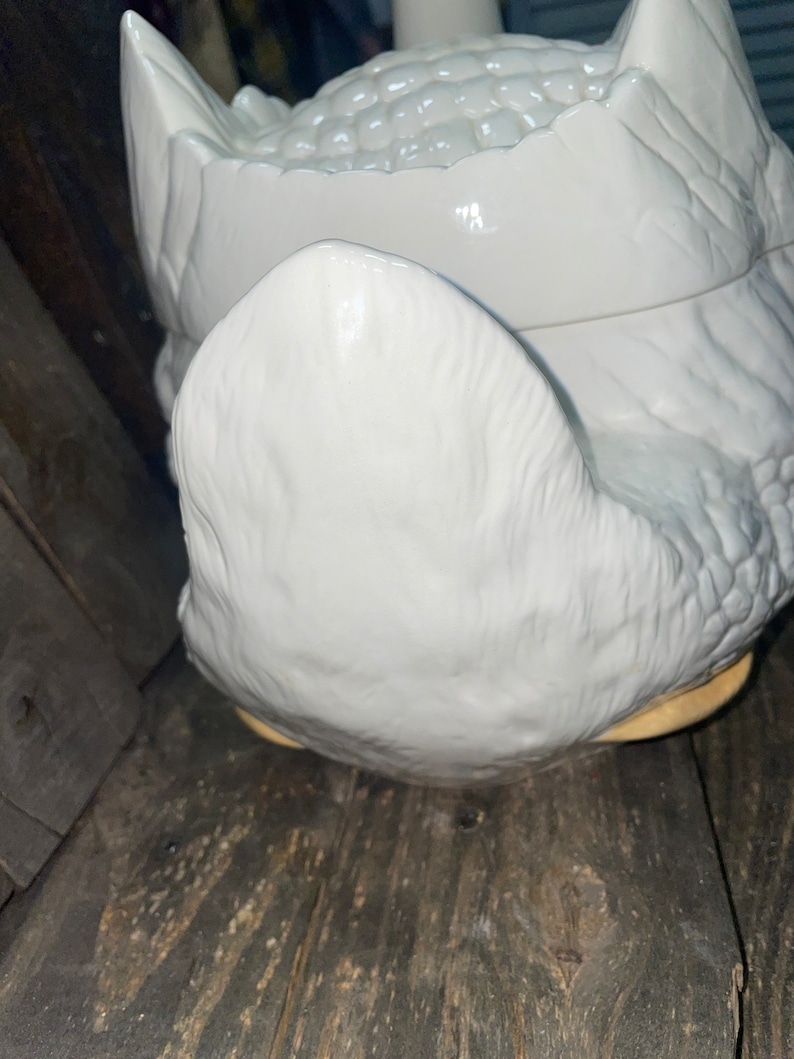 May include: White ceramic goose shaped cookie jar with a textured surface. The lid is open and the inside of the jar is visible.