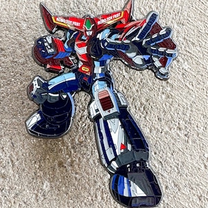 May include: A black, red, and blue robot pin with the text "Robo Toy Fest" on the wings. The robot is in a dynamic pose with its arms outstretched.