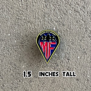 Peut inclure: Une épingle en émail noir, bleu et rouge avec un aigle noir et le texte "DEEDS NOT WORDS" et "MF". L'épingle mesure 1,5 pouce de haut.