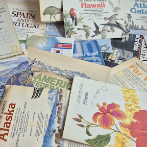 Op de afbeelding: Een verzameling vintage National Geographic kaarten en tijdschriften met diverse regionale thema's. Zichtbare titels zijn onder meer The Making of America: Hawaii, Alaska, Far West en Atlantic Gateways, naast illustraties van vogels, bloemen en landschappen.