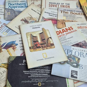 May include: A collection of vintage National Geographic maps and educational booklets featuring various titles such as The Inca, Ontario, The Southwest, and Colonization and Trade of the New World, with diverse illustrations and text printed on paper.