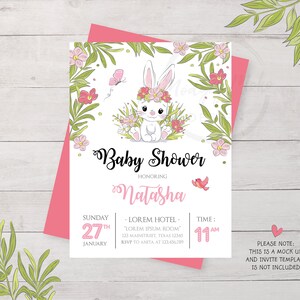 May include: A white bunny with pink ears and a pink flower crown sits in a field of green leaves and pink flowers. The text "Baby Shower" is written in a cursive font above the bunny. The text "Honoring Natasha" is written below the bunny. The text "Sunday 27th January" is written in the bottom left corner. The text "LOREM HOTEL - LOREM IPSUM ROOM" is written in the bottom center. The text "TIME: 11 AM" is written in the bottom right corner. The text "PLEASE NOTE: THIS IS A MOCK UP AND INVITE TEMPLATE IS NOT INCLUDED" is written in the bottom right corner.
