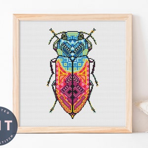Puede incluir: Un patrón de punto de cruz colorido de un escarabajo con diseños geométricos en tonos de azul, rosa, amarillo y naranja. El escarabajo está enmarcado en un marco de madera natural.