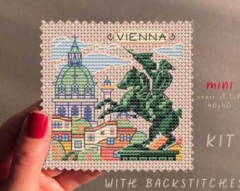 May include: A cross stitch kit featuring a colorful illustration of Vienna, Austria. The design includes a church, buildings, a knight on horseback, and the word "VIENNA". The kit is 40x40 stitches and includes backstitches.