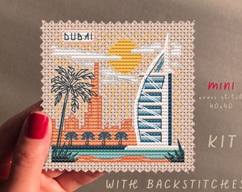 May include: A cross stitch kit featuring a colorful illustration of the Burj Al Arab hotel in Dubai, with palm trees, a sun, and the text "DUBAI". The kit is 40x40 stitches and includes backstitches.
