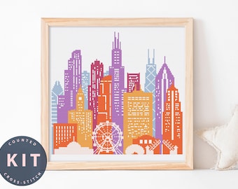 May include: A cross-stitch pattern of the Chicago skyline in a wooden frame. The buildings are in shades of orange, red, purple, and blue. The pattern includes a Ferris wheel.