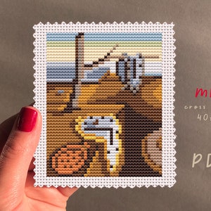 May include: A cross stitch pattern of The Persistence of Memory by Salvador Dalí, a surrealist painting featuring melting clocks. The pattern is 40 stitches wide by 50 stitches high. The pattern is labeled "mini cross stitch 40x50 PDF".