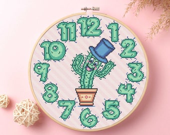 May include: A cross-stitch embroidery hoop with a cactus wearing a hat and numbers 1 through 12 around the edge.
