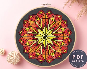 May include: A counted cross stitch pattern featuring a colorful geometric mandala with red, orange, and yellow hues. The pattern is displayed in a wooden embroidery hoop on a pink background. The text "COUNTED PDF pattern CROSS-STITCH" is visible in the lower right corner.