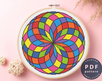 May include: A counted cross stitch pattern featuring a colorful geometric design of a sphere with a rainbow color scheme. The pattern is displayed on a wooden embroidery hoop.
