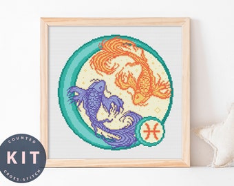 May include: A counted cross stitch kit featuring a circular design with two fish, one orange and one purple, swimming in a turquoise circle with a white background. The symbol for Pisces is in the bottom right corner of the circle.