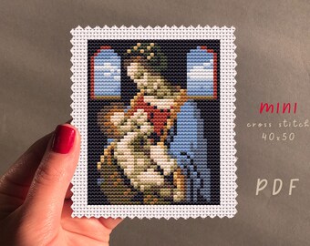 May include: A cross stitch pattern of a painting of the Virgin Mary holding a baby Jesus. The pattern is in a white frame with a scalloped edge. The pattern is labeled "mini cross stitch 40x50 PDF".