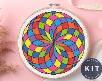 May include: A counted cross stitch kit featuring a colorful geometric design of a sphere with a rainbow color scheme. The kit includes a pattern and all the necessary materials to complete the project. The finished piece is framed in a wooden hoop.