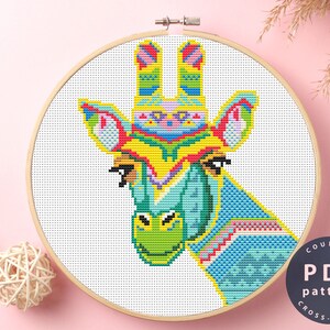 May include: A counted cross stitch pattern featuring a colorful giraffe head with a blue, green, yellow, red, and pink design. The pattern is in a wooden embroidery hoop.