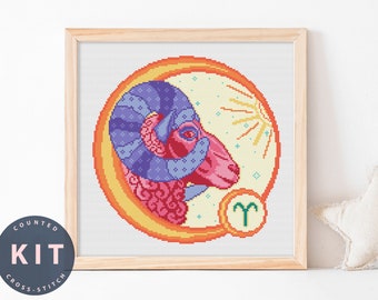 May include: A counted cross stitch kit featuring a colorful illustration of the zodiac sign Aries, a ram's head with a purple and pink design, surrounded by a yellow and orange circle with a sun and stars. The symbol for Aries is in the lower right corner.