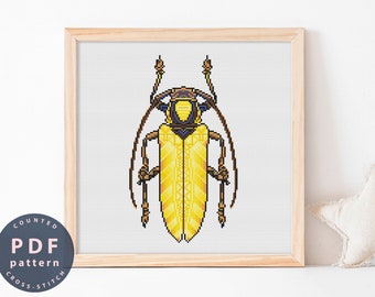 May include: A counted cross stitch pattern featuring a yellow and blue beetle with long antennae. The pattern is framed in a light wood frame.