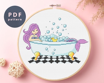 May include: Cross stitch pattern featuring a mermaid taking a bath in a white bathtub with a yellow rubber ducky. The mermaid has long purple hair and a purple tail. There are blue bubbles around her.