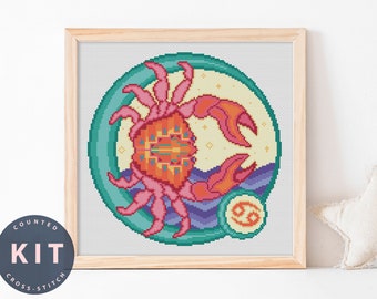 May include: A counted cross stitch kit featuring a colorful illustration of the Cancer zodiac sign. The design includes a crab with pink claws and a yellow body, surrounded by a teal circle with a purple and blue wave pattern. The Cancer symbol is in the lower right corner.