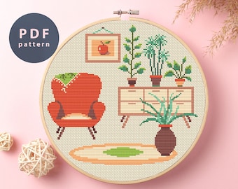 May include: Cross stitch pattern of a living room with a red armchair, a dresser with plants, and a rug. The pattern is in a hoop and ready to be stitched.