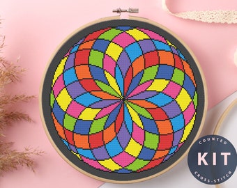 May include: A counted cross stitch kit featuring a colorful geometric design of a sphere with a black background. The kit includes all the materials needed to complete the project. "COUNTED KIT CROSS STITCH" is printed on a blue circle.