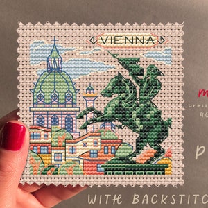 May include: A cross stitch pattern of Vienna, Austria, featuring the St. Stephen's Cathedral, the equestrian statue of Prince Eugene of Savoy, and other buildings. The pattern is 40x40 stitches and includes backstitches. The pattern is labeled "VIENNA" and "mini cross stitch".