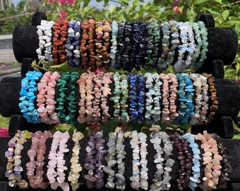 May include: A collection of 20 chip bracelets made with various semi-precious stones. The bracelets are stacked on a black display stand. The stones include amethyst, rose quartz, tiger's eye, turquoise, lapis lazuli, and more.