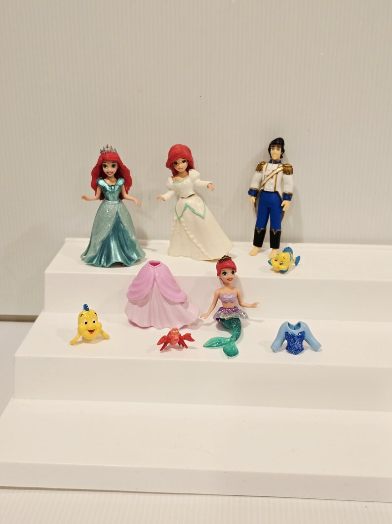 K&ouml;nnte beinhalten: Eine Sammlung von Miniaturfiguren mit Charakteren aus einem beliebten Zeichentrickfilm. Das Set enth&auml;lt eine Meerjungfrau, einen Prinzen und andere Charaktere. Die Figuren sind farbenfroh und aus Kunststoff.