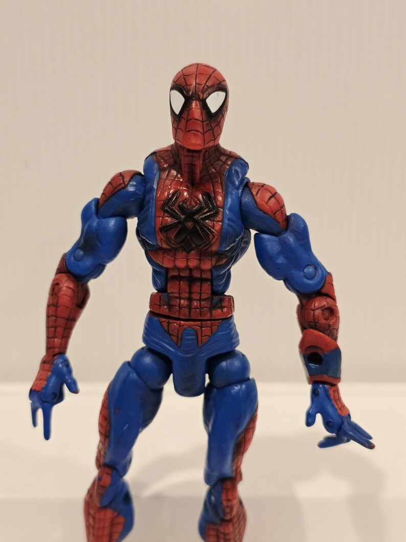 Pode incluir: Figura de a&ccedil;&atilde;o do Homem-Aranha com um traje vermelho e azul. A figura tem uma m&aacute;scara vermelha com lentes brancas, um emblema de aranha preta no peito e articula&ccedil;&otilde;es. A figura tem aproximadamente 15 cm de altura.