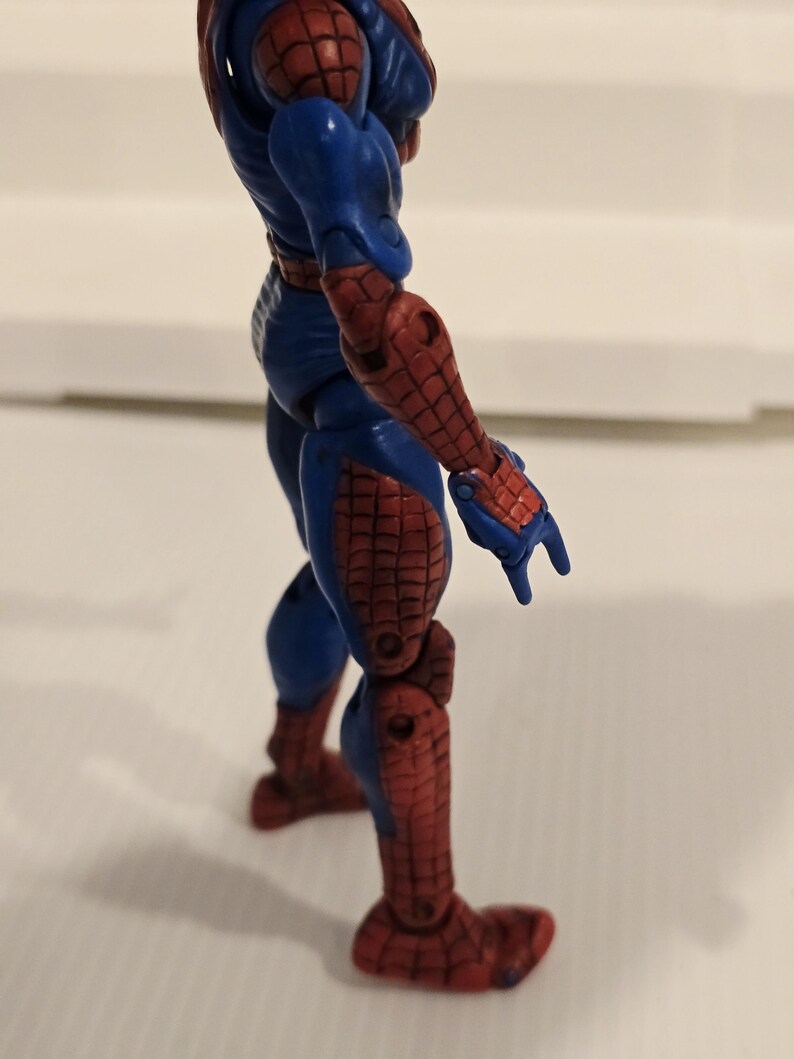 Pode incluir: Figura de a&ccedil;&atilde;o azul e vermelha de um super-her&oacute;i. A figura tem uma constru&ccedil;&atilde;o muscular, com se&ccedil;&otilde;es vermelhas nos bra&ccedil;os, pernas e p&eacute;s, e azul no torso e nas articula&ccedil;&otilde;es. A figura est&aacute; em uma pose din&acirc;mica.