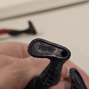 May include: Close-up of a black action figure's foot, with the text "&copy; 2005 Marvel" and "&copy; 2005 CPII" imprinted on the sole. The figure has a textured, web-like design.