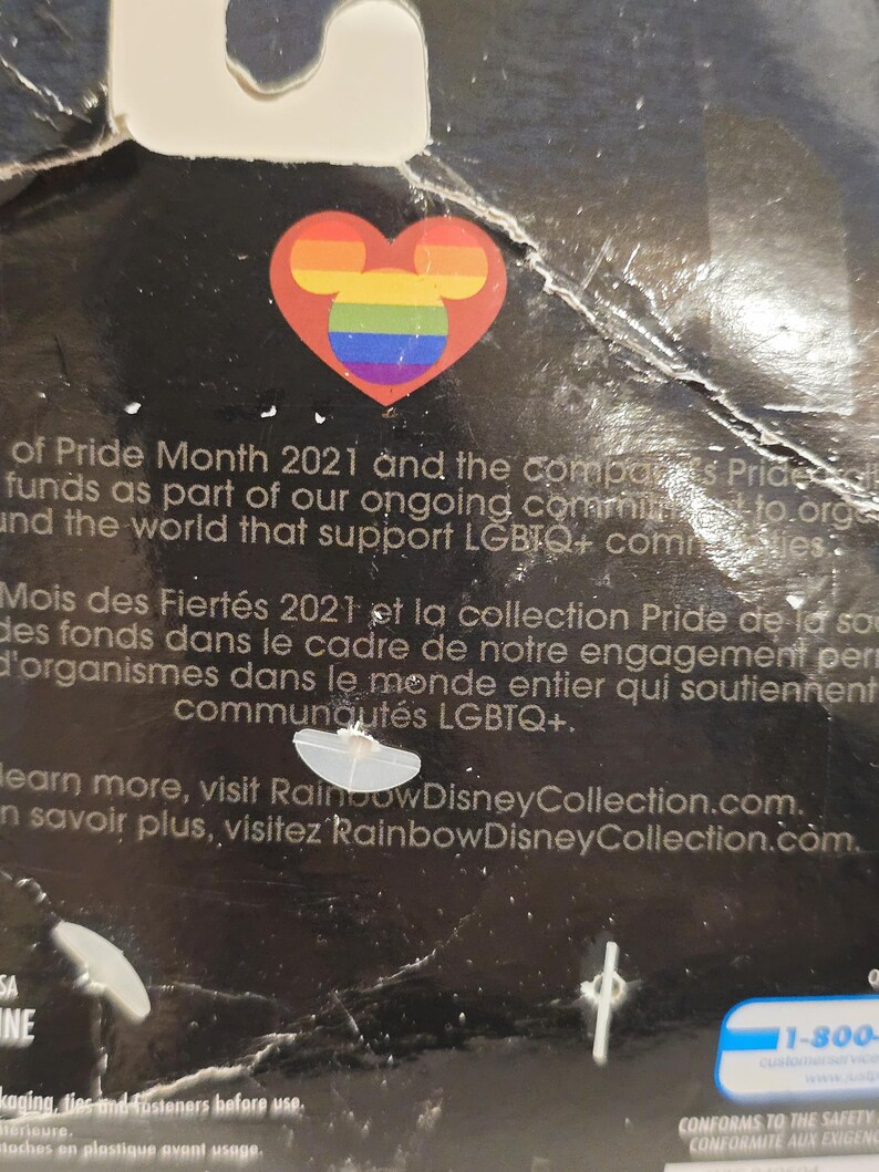 May include: A black product package featuring a rainbow-colored Mickey Mouse head inside a red heart. The text mentions Pride Month 2021 and support for LGBTQ+ communities. Visit RainbowDisneyCollection.com.