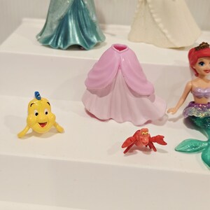 K&ouml;nnte beinhalten: Eine Sammlung von Disney-Figuren mit Charakteren aus Arielle, die Meerjungfrau. Die Figuren umfassen Arielle, Fabius, Sebastian und andere Charaktere. Die Figuren sind aus Kunststoff und farbenfroh.