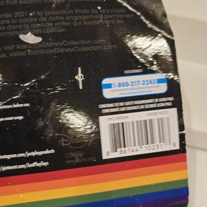 May include: A product package with a rainbow-colored stripe design at the bottom. The package has text in English and French, along with a barcode and the Disney logo. A customer service phone number is also visible.