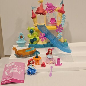 K&ouml;nnte beinhalten: Ariel's Sea Castle Spielset mit einem farbenfrohen Schloss, einer Rutsche, einem Boot und Figuren. Das Schloss hat rosa, gelbe und blaue Akzente, mit einer Rutsche und dekorativen Elementen. Enth&auml;lt zwei Ariel-Figuren, ein Boot und Zubeh&ouml;r.