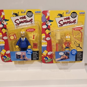 May include: Two Playmates World of Springfield interactive figures. One features Homer Simpson in a blue suit with accessories. The other is Bart Simpson with a bow and arrow. Both are in original packaging with yellow and red accents.