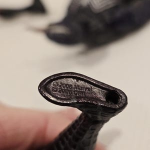 May include: Close-up of a dark, textured, snake-like figurine. The base of the figurine has the text "&copy;2006 Marvel" and "&copy;2006 CPI". The figurine is dark in color and appears to be made of plastic.