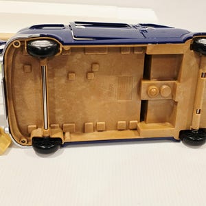 May include: A blue toy car with black wheels and a tan undercarriage. The car has a shiny finish and chrome accents. The wheels are attached to the car with silver rods.