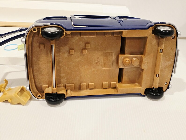 May include: A blue toy car with black wheels and a tan undercarriage. The car has a shiny finish and chrome accents. The wheels are attached to the car with silver rods.