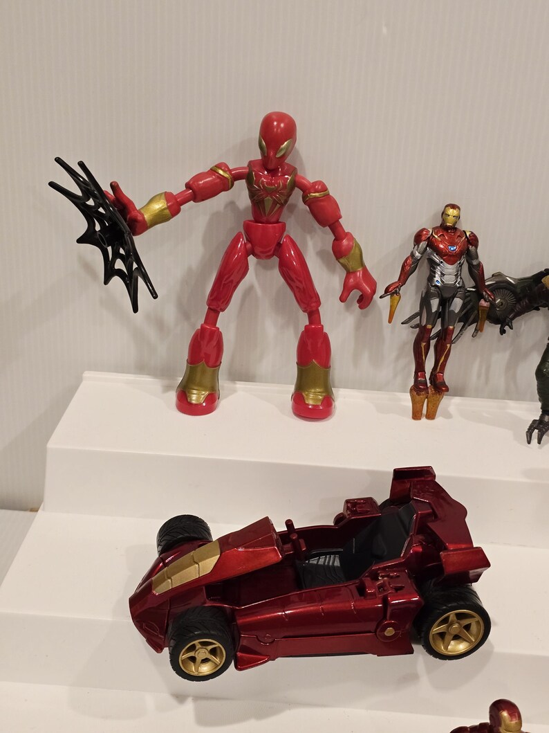 May include: A collection of red and gold action figures and a red race car toy. The Spider-Man figure is red with gold accents and a black web accessory. The race car is red with gold wheels.
