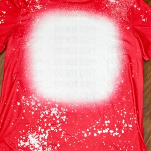 May include: Red t-shirt with a white bleach splattered design. The design is a large circle in the center of the shirt with smaller splatters around it.