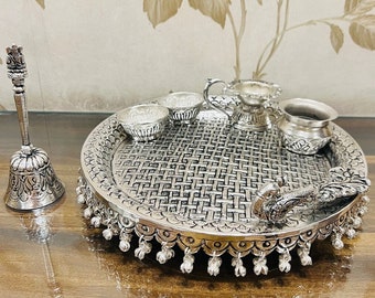 May include: A silver-plated tray with a peacock design handle, surrounded by small bowls and a pitcher. The tray has a woven pattern and a decorative border.
