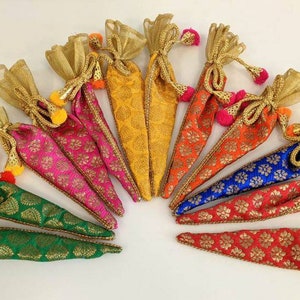 Puede incluir: Surtido de bolsitas cónicas de colores con ribetes dorados y borlas. Las bolsitas están hechas de tela con estampado floral y están atadas con una cinta dorada.