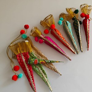 May include: A set of seven colorful cone-shaped pouches with gold trim and tassels. The pouches are made of fabric and have a variety of patterns.