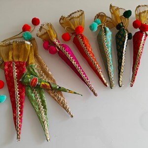 May include: Six colorful cone-shaped pouches with gold trim and pom-poms, filled with henna paste. The pouches are made of fabric and have a traditional Indian design.