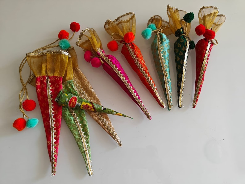 May include: Six colorful cone-shaped pouches with gold trim and pom-poms, filled with henna paste. The pouches are made of fabric and have a traditional Indian design.