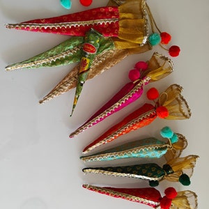 May include: Set of six colorful cone-shaped pouches with gold trim and pom-poms. Each pouch is made of fabric and has a sheer overlay. The pouches are arranged in a row, with the largest pouch at the top and the smallest pouch at the bottom. The pouches are filled with henna paste.