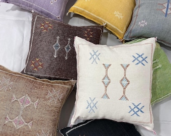May include: Assortment of colorful throw pillows with geometric patterns and embroidery. The pillows are made of a soft, textured fabric and feature a variety of colors, including purple, blue, yellow, brown, white, black, and green.
