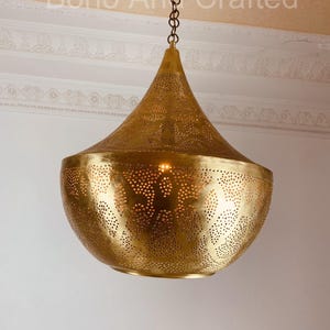 May include: A gold-toned, round, hanging pendant light fixture with a decorative, perforated pattern. The light fixture is suspended from a chain.