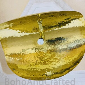 May include: A gold-toned, hammered metal ceiling light fixture with a single light bulb.