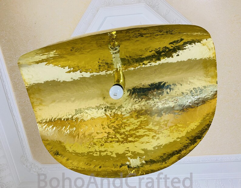 May include: A gold-toned, hammered metal ceiling light fixture with a single light bulb.